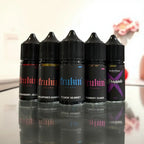 Five FCUKIN' FLAVA vape juice bottles in flavors like Strawberry Jello and Yummay Guava, displayed on reflective surface