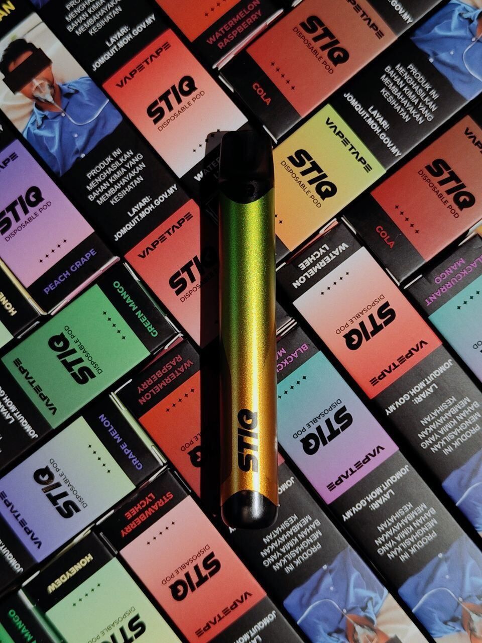 STIQ disposable vape pod with colorful flavor boxes, featuring metallic green and gold design